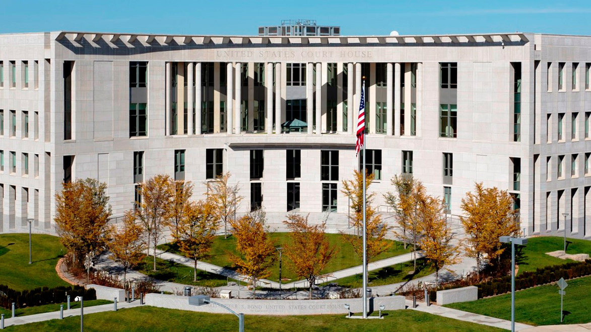 A light colored stone multi-story building that curves inward and has United States Court House engraved on the top.